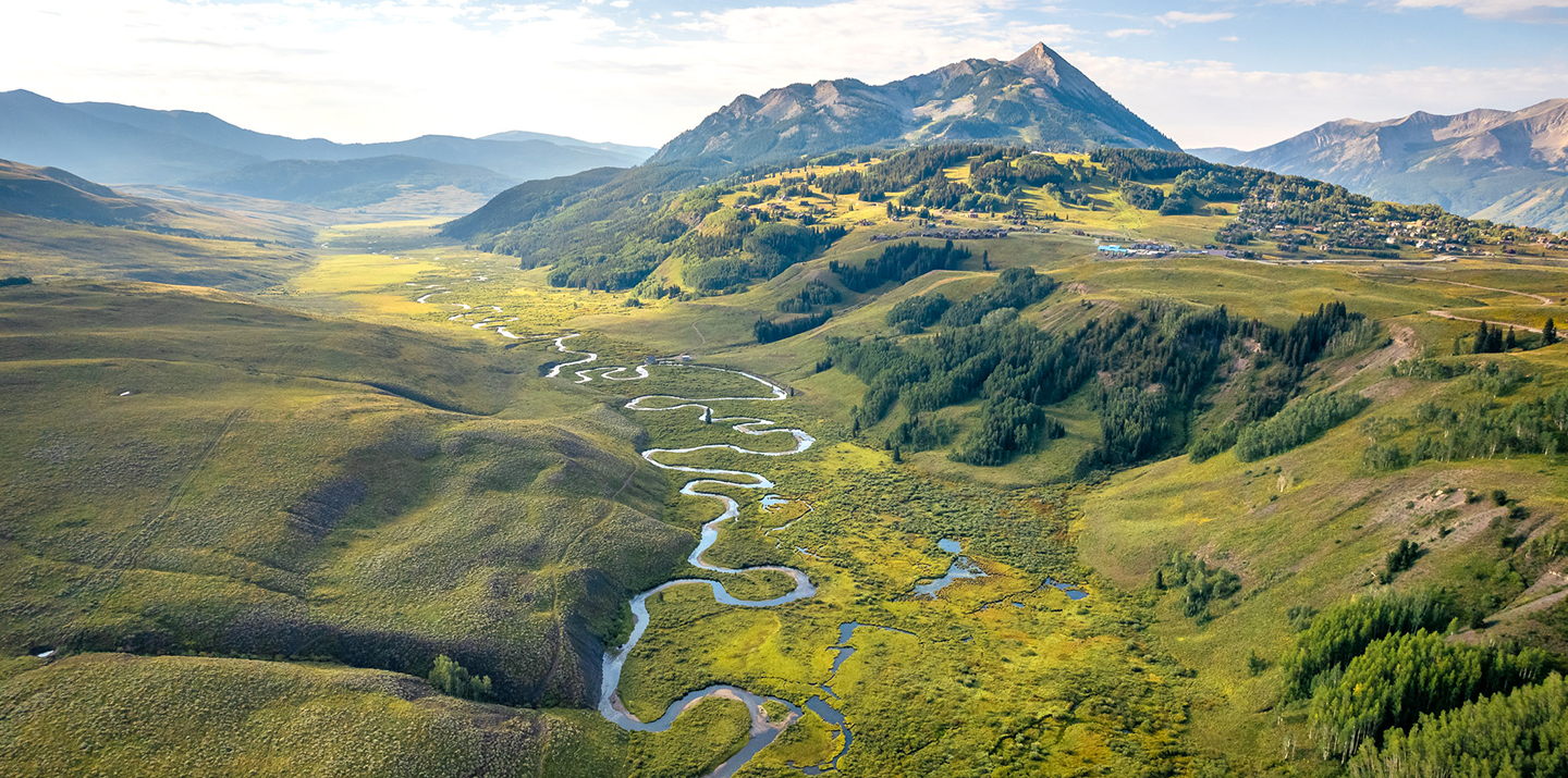Aerial view of winding river through lush green mountain valley