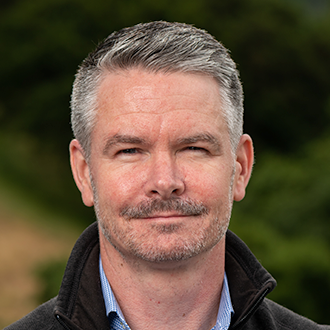 Headshot of Eoin Brodie, a white man with salt-and-pepper hair and a mustache